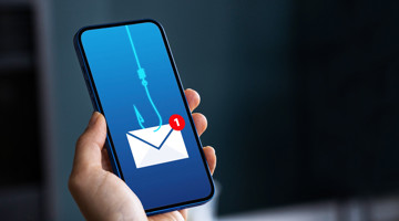 Een hand houdt een smartphone met een visuele melding van een phishing-e-mail, weergegeven door een haak die een envelop vangt.